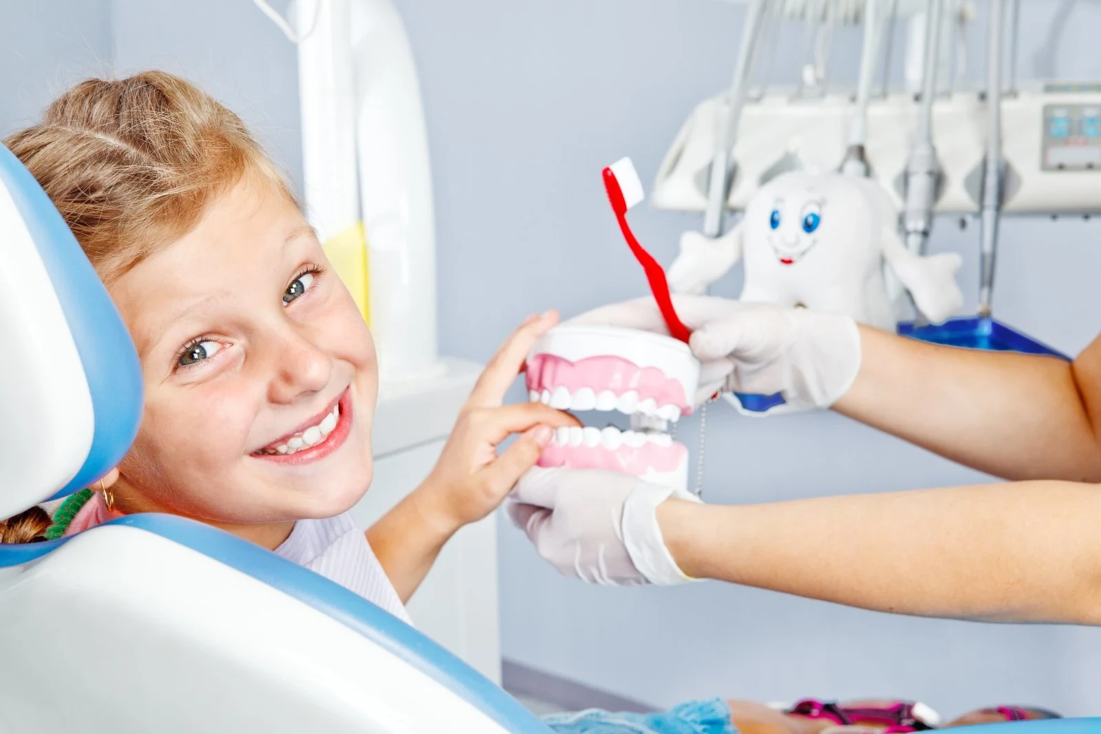 Pediatric preventive dentistry in Gardner, KS at Sunshine Smiles Pediatric Dentistry with smiling child learning brushing using tooth model